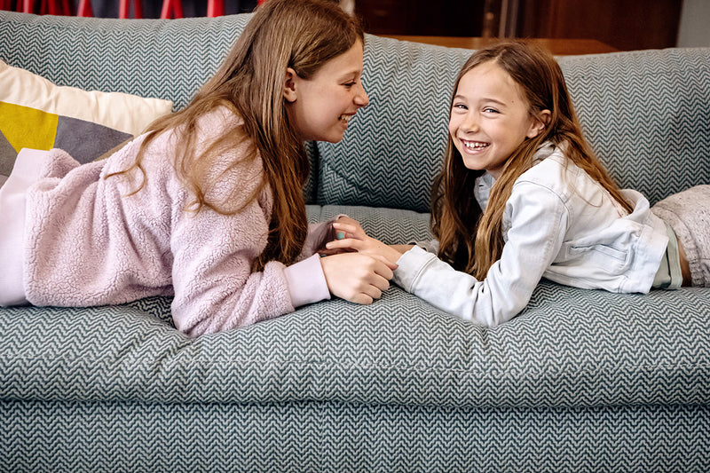 Two children laughing on sofa